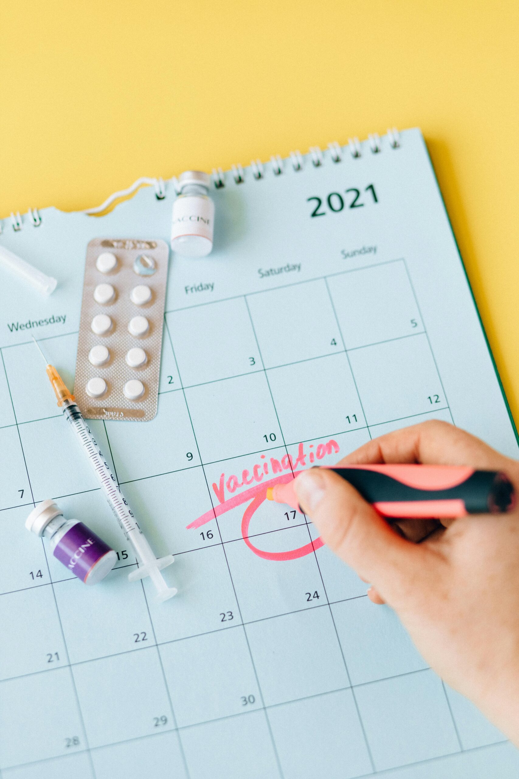 A calendar marked with a vaccination date, syringe, and medicine vials symbolize health protection.